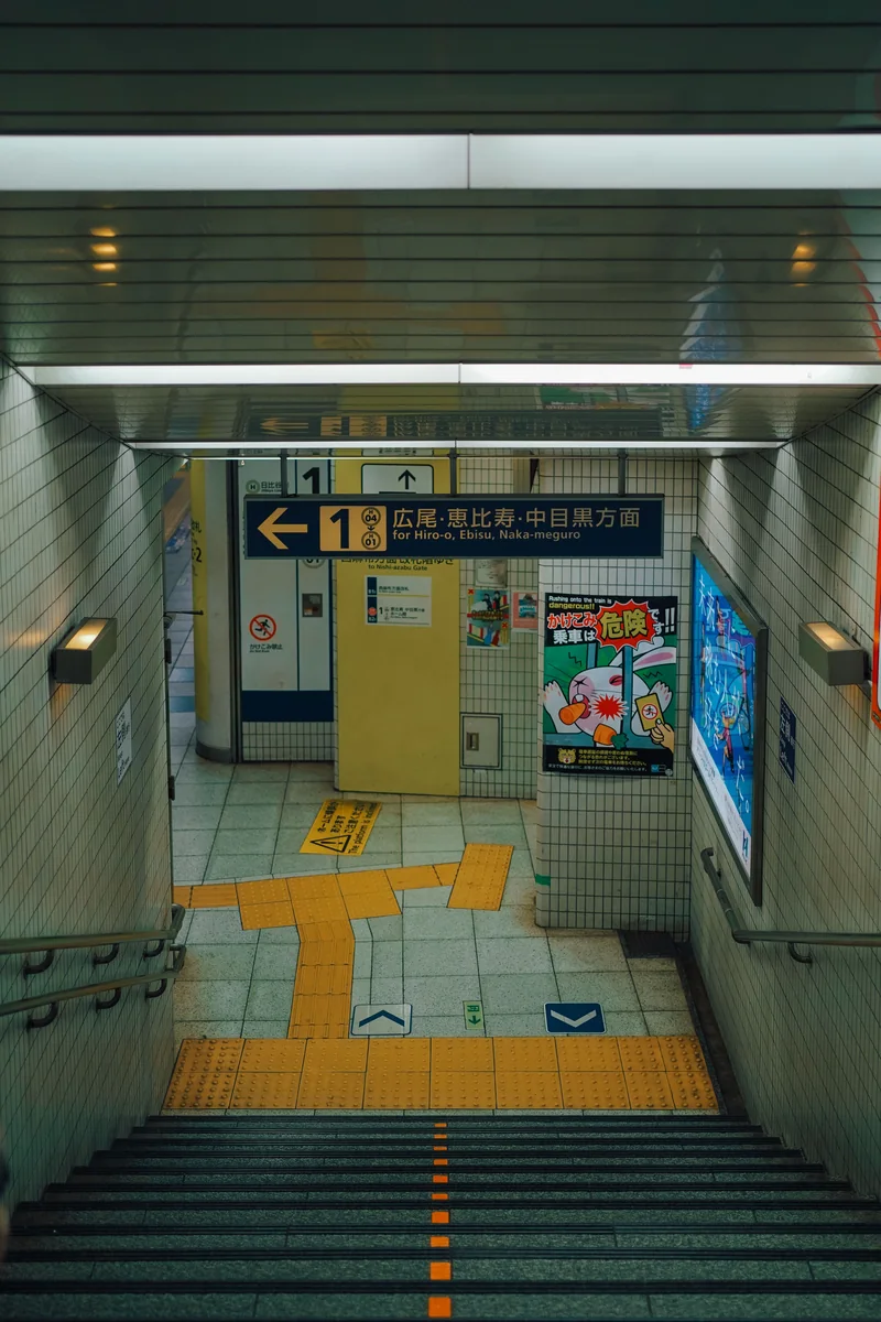 Cầu thang trong ga tàu điện với biển chỉ hướng về Hiroo, Ebisu và Nakameguro.
