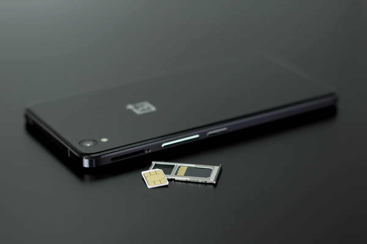 Điện thoại màu đen đặt cạnh SIM vật lý và khay SIM.
